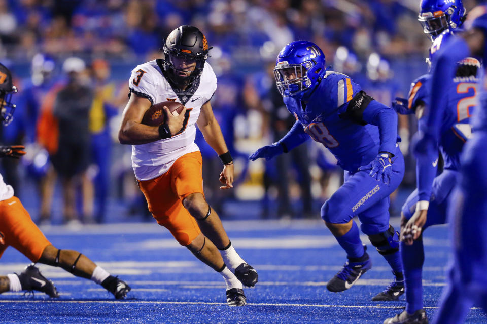 Oklahoma State quarterback Spencer Sanders (3) runs with the ball past Boise State defensive end Demitri Washington (38) during the first half of an NCAA college football game Saturday, Sept. 18, 2021, in Boise, Idaho. (AP Photo/Steve Conner)