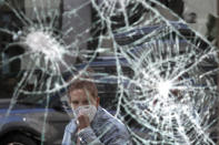 FILE - In this Monday, June 1, 2020 file photo, a woman wearing a mask due to coronavirus concerns, looks at a smashed storefront window in Boston's Downtown Crossing. The destruction caused by vandals and looters in cities across the country, who struck as demonstrators took to the streets in reaction to the killing of George Floyd in Minneapolis, has devastated small businesses already reeling from the coronavirus outbreak. (AP Photo/Elise Amendola, File)