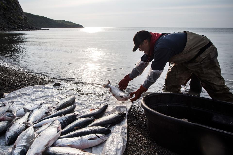 Joseph John Jr. washes freshly caught salmon with his son, Jeremiah John, while waiting for the tide to come in July 1, 2015, in Newtok, Alaska. Newtok was established along the shores of the Ninglick River, near where the river empties into the Bering Sea. As global temperatures rise, the village is being threatened by the melting of permafrost, greater ice and snow melt and larger storms from the Bering Sea.