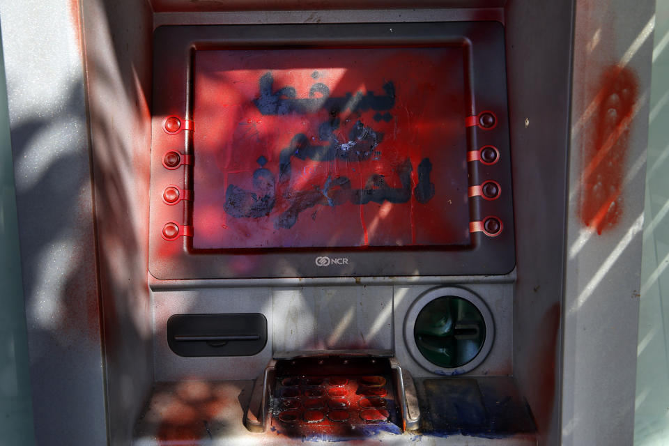 A damaged ATM screen has been spray painted with a message that reads in Arabic, "Down with the rule of the banks," in Beirut, Lebanon, Tuesday, Nov. 12, 2019. Lebanon's banking association says banks will stay closed due to a strike by employees, as country's financial crisis worsens. (AP Photo/Bilal Hussein)