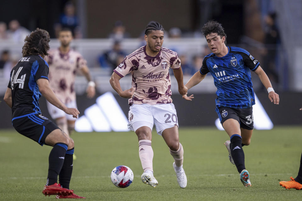 San Jose Earthquakes midfielder Niko Tsakiris, right, and forward Cade Cowell, left, defend against Portland Timbers midfielder Evander (20) during the first half of an MLS soccer match in San Jose, Calif., Saturday, June 17, 2023. (AP Photo/John Hefti)