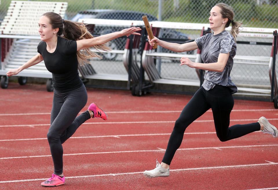 South Kitsap's Elise Hopper (right) passes the baton to sister Ella as they practice handoffs in Port Orchard on Tuesday, May 10, 2022. 