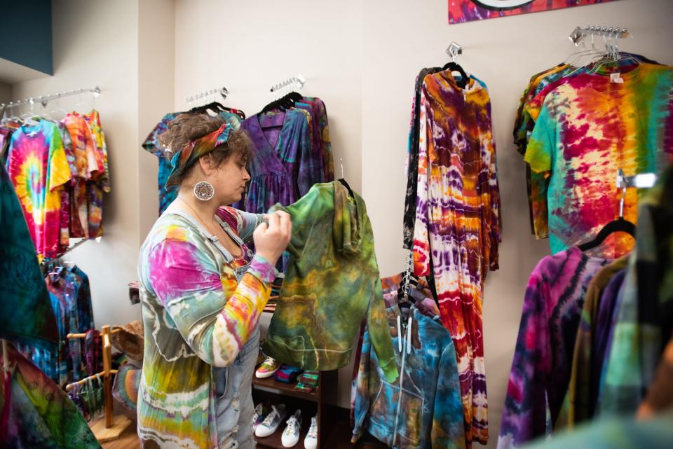 "I'm kinda living my dream," Middle Village vendor Laura Castle of Capital Hippie says while hanging her tie-dyed wares Wednesday afternoon, March 16, 2022, at Middle Village Micro Market in downtown Lansing. She had problems getting large tie-dyes shirts in her size, so began making them for herself. She soon discovered there was a market for shirts. "I can make tie dye shirts as large as 5x and more."