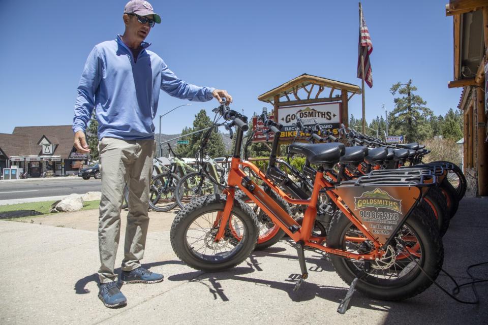 A business owner stands with e-bikes for rent