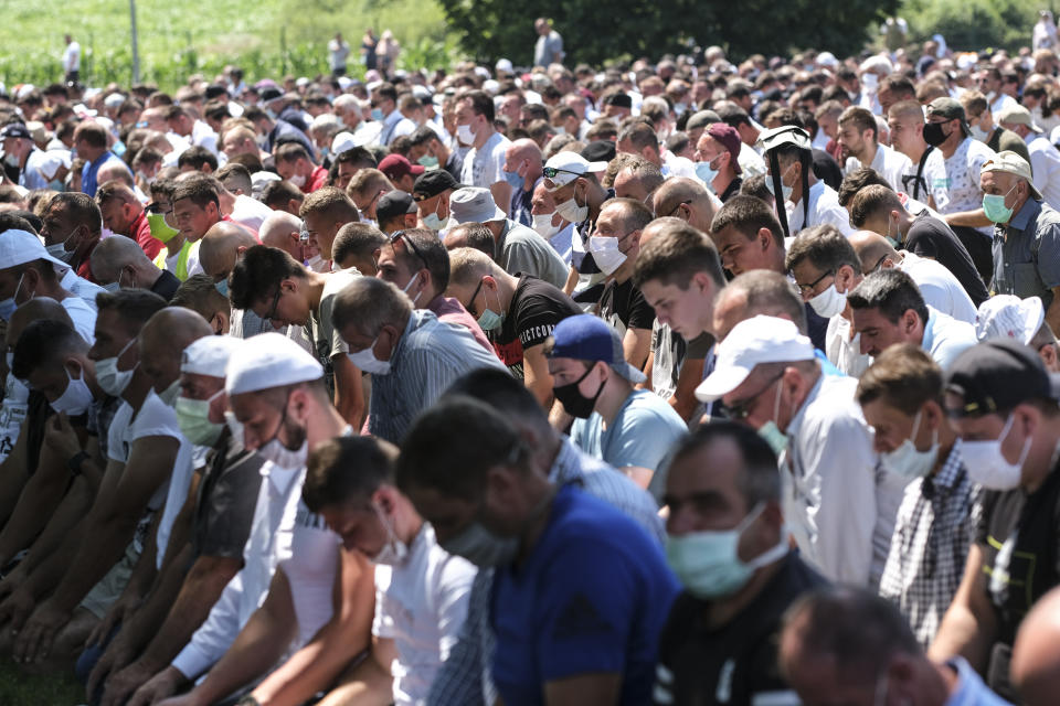 Bosnian pray by the coffins of the victims during the burrial in Potocari, near Srebrenica, Bosnia, Saturday, July 11, 2020. Mourners converged on the eastern Bosnian town of Srebrenica for the 25th anniversary of the country's worst carnage during the 1992-95 war and the only crime in Europe since World War II that has been declared a genocide. (AP Photo/Kemal Softic)