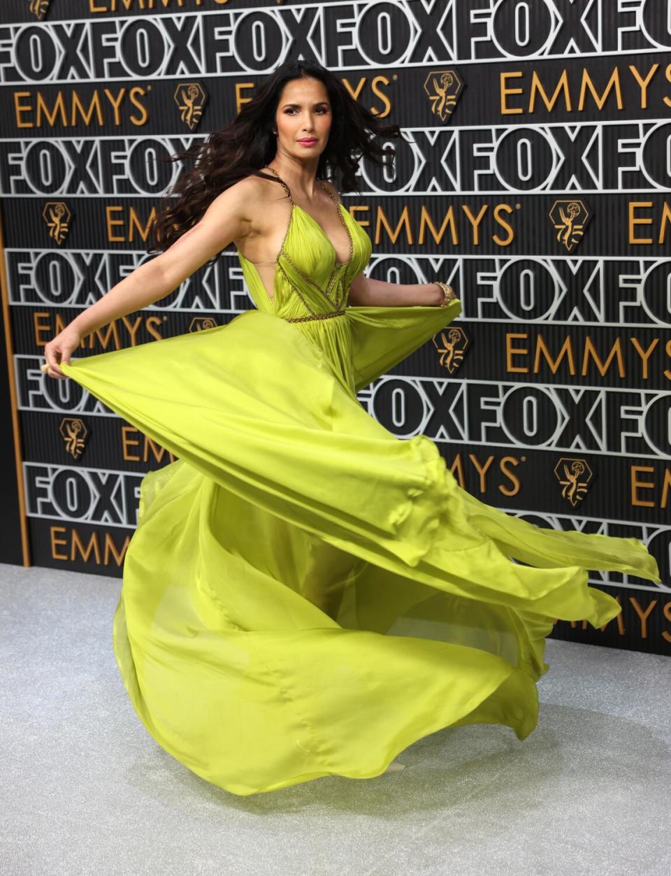 Padma Lakshmi wears a green dress and twirls on the Emmys red carpet.