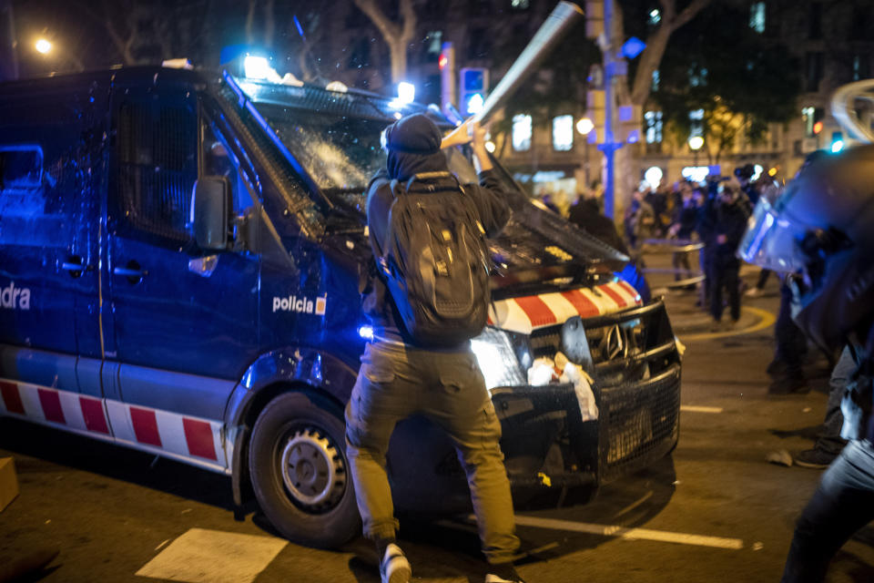 A demonstrator hits a police van with a bat during clashes following a protest condemning the arrest of rap singer Pablo Hasél in Barcelona, Spain, Wednesday, Feb. 17, 2021. Police fired rubber bullets and baton-charged protesters as clashes erupted for a second night in a row Wednesday at demonstrations over the arrest of Spanish rap artist Pablo Hasél. Many protesters threw objects at police and used rubbish containers and overturned motorbikes to block streets in both Madrid and Barcelona. (AP Photo/Emilio Morenatti)