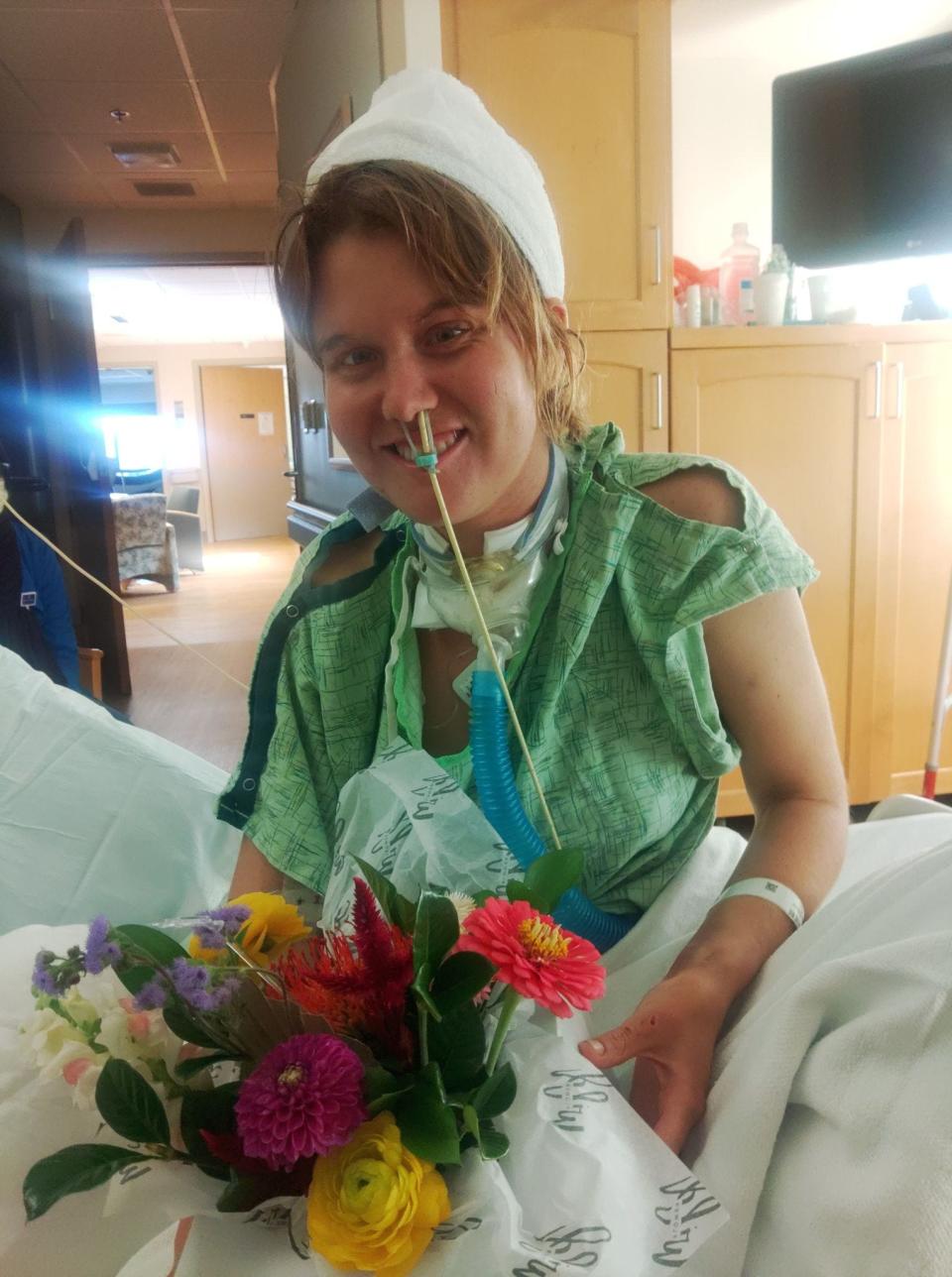 Sierra DesPlanques poses with flowers in her hospital room at Iowa Methodist Medical Center in Des Moines.