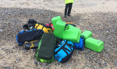 A law enforcement officer stands by holdalls containing cocaine that were washed up on Hopton Beach, near Great Yarmouth, Britain February 9, 2017. Photograph taken February 9, 2017. National Crime Agency/Handout via Reuters