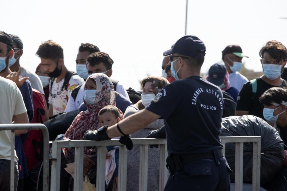 Migrants wait to enter a new temporary refugee camp in Kara Tepe,near Mytilene the capital of the northeastern island of Lesbos, Greece, Thursday, Sept. 17, 2020. Greek police are moving hundreds of migrants to an army-built camp on the island of Lesbos Thursday after a fire destroyed an overcrowded facility, leaving them homeless for days. (AP Photo/Petros Giannakouris)