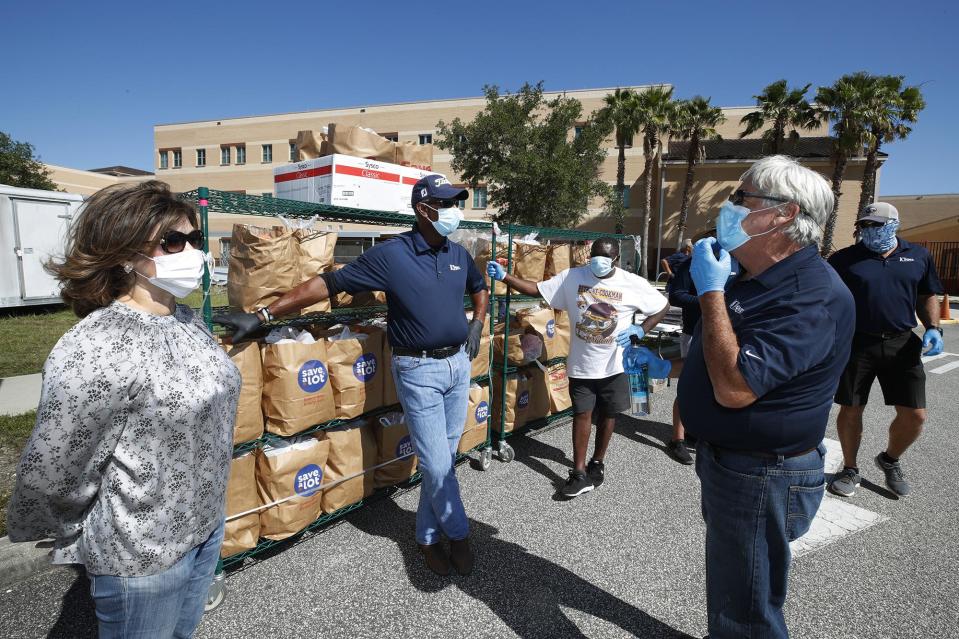 Forough Hosseini, with volunteers with Food Brings Hope, ICI, Embry Riddle and Sodexo, hand out grocery bags full of food during a food giveaway at Mainland High School in Daytona Beach, Thursday, May 7, 2020.