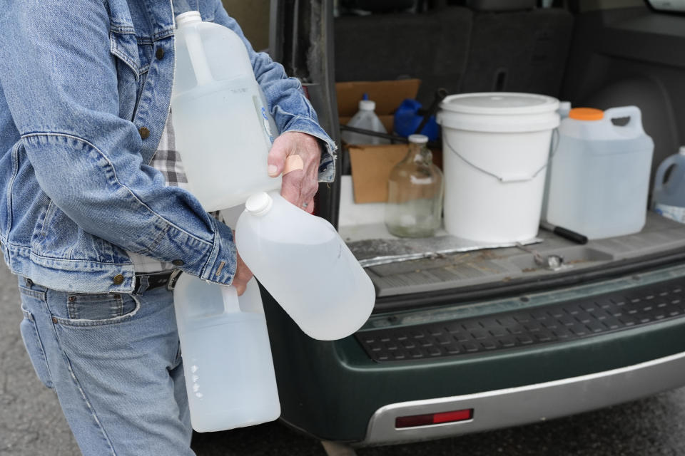 Larry Camper carries water jugs to his vehicle Wednesday, Jan. 24, 2024, in Mason, Tenn. A winter storm brought sub-freezing temperatures and snow to Mason and the rest of Tennessee last week. The cold caused the town's pipes to freeze over and break, creating leaks that lowered water pressure. The cold exposed major problems with a water system that dates back to the 1950s. (AP Photo/George Walker IV)