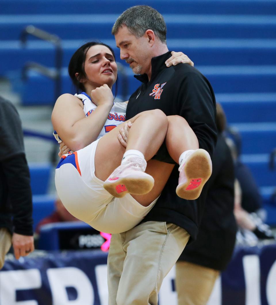 Southwestern head coach Junior Molden carried his daughter Kinsley Molden (24) off the court after she was injured against Bullitt East during the Girls LIT at the Valley High School gym in Louisville, Ky. on Jan. 25, 2023.  