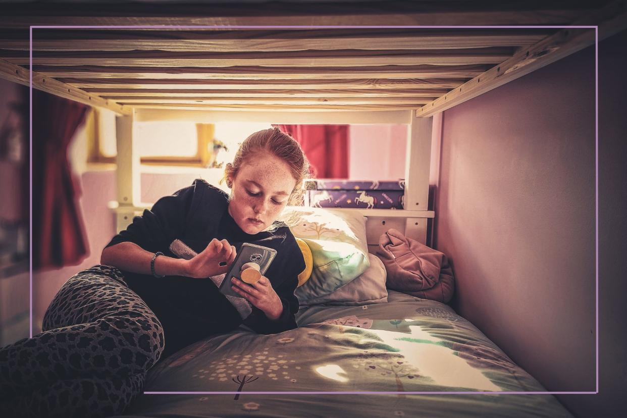  Tween lying on bed with smartphone. 