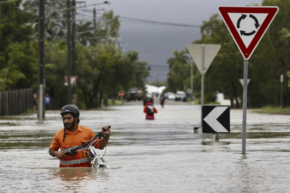 In this Sunday, Feb. 3, 2019, photo, a resident pushes a bicycle through floodwaters at Hermit Park in Townsville, Australia. Emergency workers are using boats and helicopters to rescue people from flooded parts of northern Australia where forecasts call for more heavy rainfall. More than 1,100 people had been rescued from their homes on Sunday night and evacuation efforts were continuing Monday. (Andrew Rankin/AAP Image via AP)