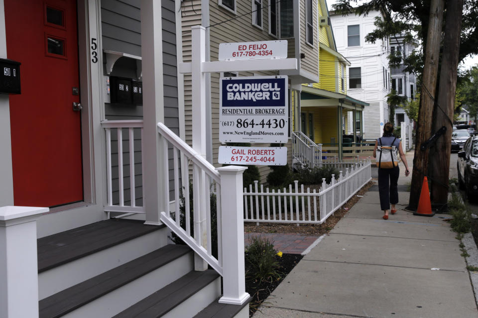 In this Tuesday, Aug. 13, 2019, photo a woman walks past a home listed in Cambridge, Mass. On Thursday, Aug. 15, Freddie Mac reports on this week’s average U.S. mortgage rates. (AP Photo/Charles Krupa)