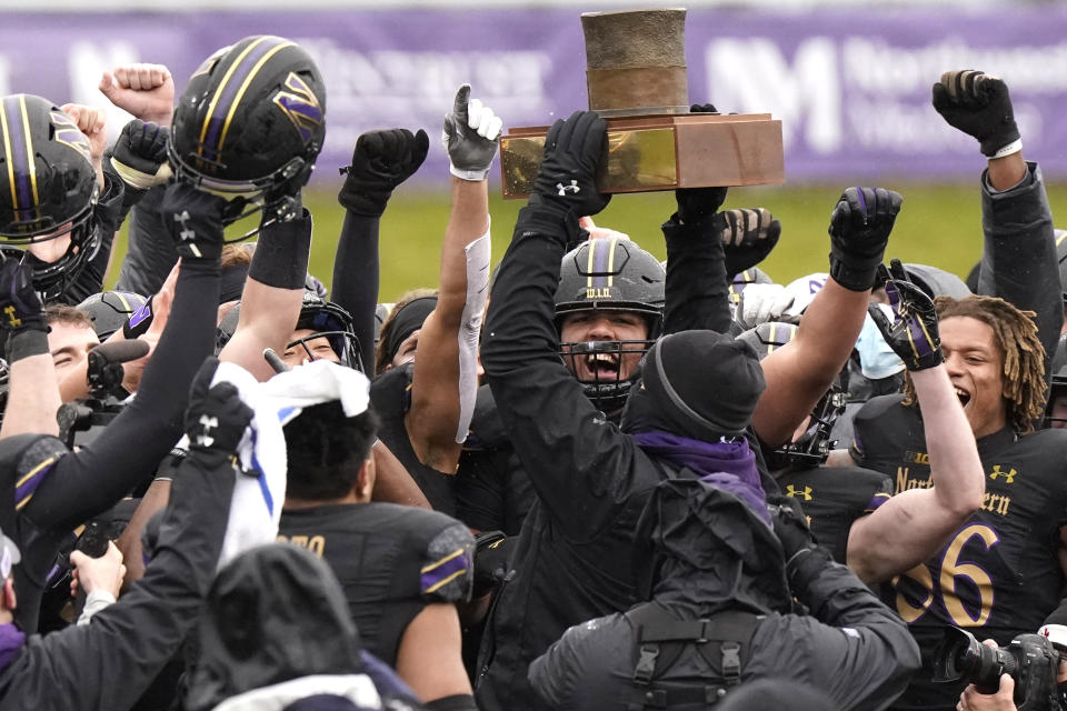 Northwestern football head coach Pat Fitzgerald celebrates with players as he holds the Land of Lincoln Trophy after Northwestern defeated Illinois 28-10 in an NCAA college football game in Evanston, Ill., Saturday, Dec. 12, 2020. (AP Photo/Nam Y. Huh)