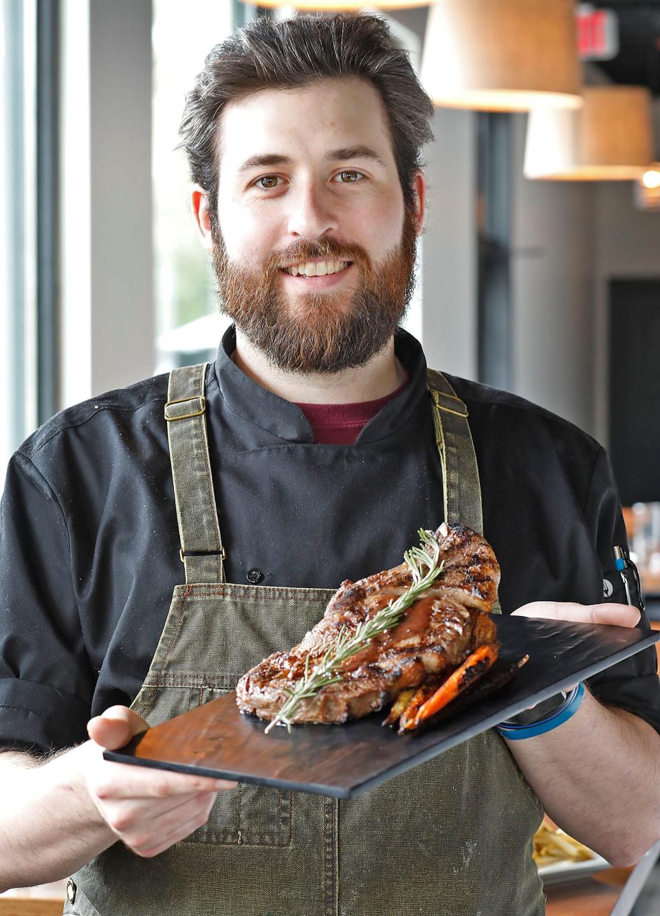 Chef Zach Prifti holds a cowboy ribeye steak at The Blacksmith Tavern on Washington Street in Pembroke on Thursday, May 12, 2022.