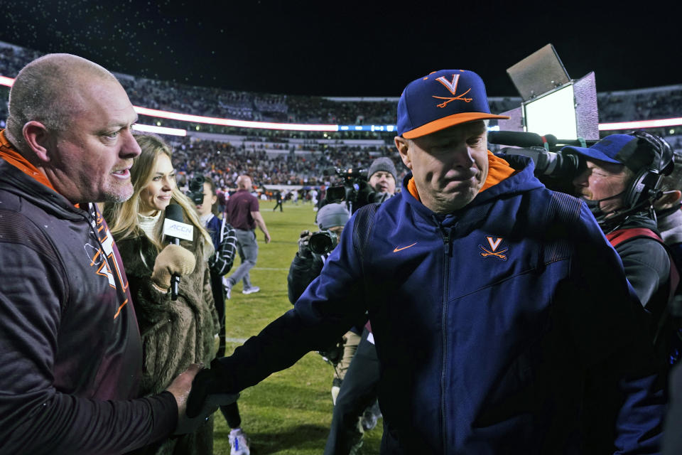 Virginia Tech head coach J.C. Price, left, shakes the hand of Virginia head coach Bronco Mendenhall after an NCAA college football game Saturday Nov 27, 2021, in Charlottesville, Va. Tech won the game 29-24. (AP Photo/Steve Helber)