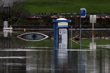 A bus stop and a car sit in the flooded waters of the Stillaguamish River in Stanwood, Washington November 18, 2015. REUTERS/David Ryder