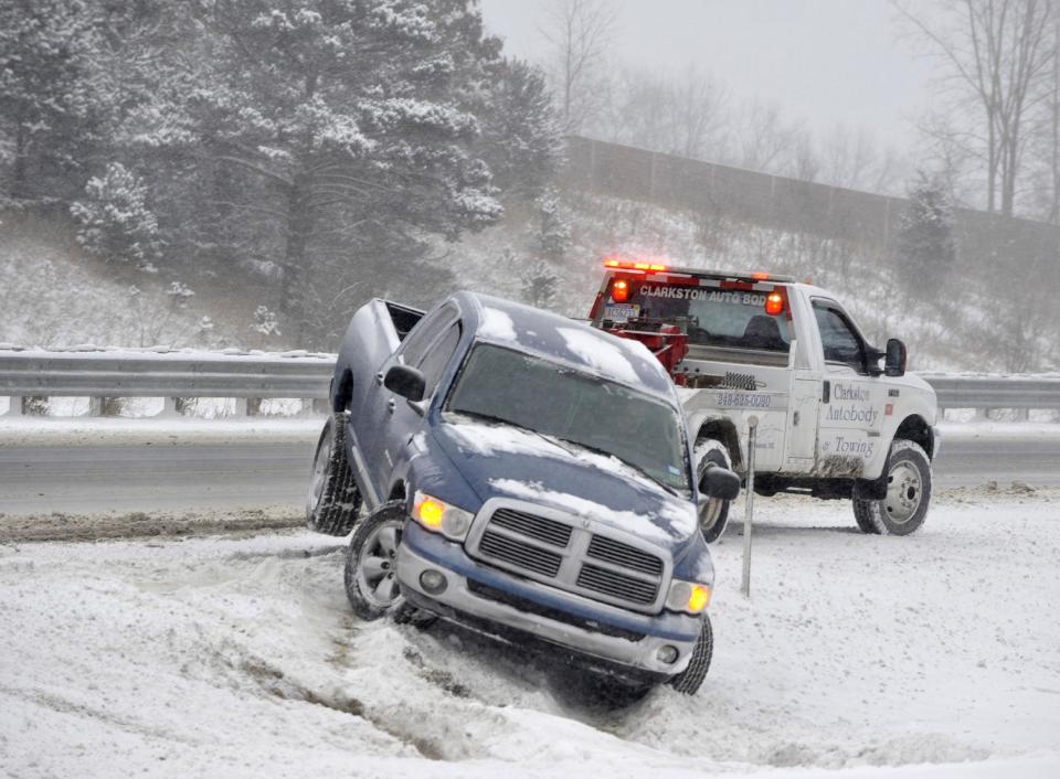 A pickup trucked is pulled out of the snow along southbound I-75 near Dixie Highway by a tow truck in Clarkston, Mich., Thursday, Jan. 2, 2014. Roads were slippery and snow-covered in Detroit and its suburbs for the Thursday morning commute. (AP Photo/Detroit News, Charles V. Tines) DETROIT FREE PRESS OUT; HUFFINGTON POST OUT, MADATORY CREDIT