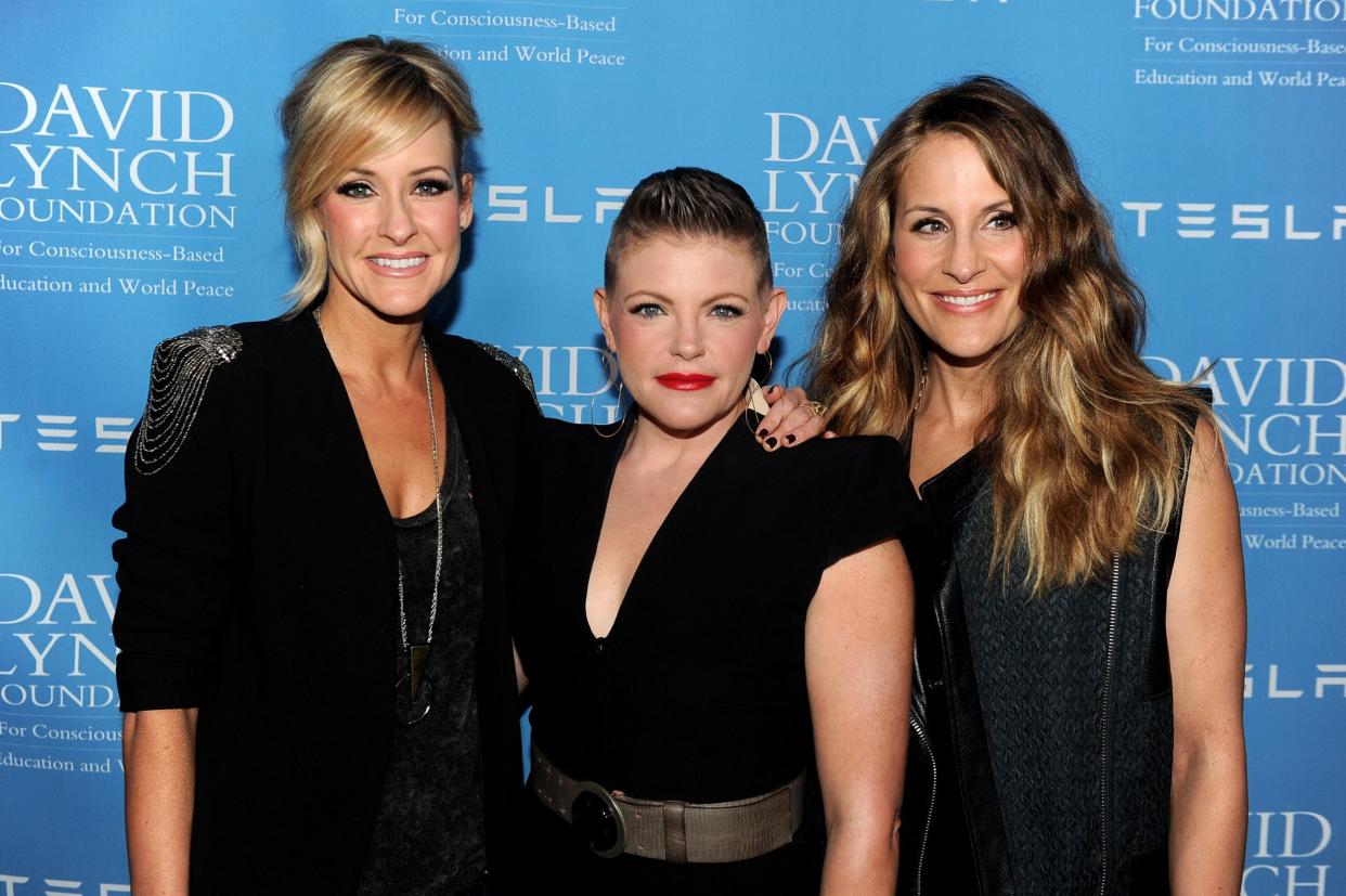 Musicians Martie Maguire, Natalie Maines and Emily Robison of the Dixie Chicks in Beverly Hills, standing in front of a blue background with advertising, 2014