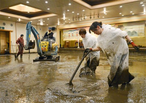 Workers shovel muddy water out of a banquet room of a hotel in Aso, Kumamoto Prefecture, Japan, Saturday, July 14, 2012. Heavy rain triggered flash floods and mudslides in southern Japan this week, killing nearly two dozens of people. (AP Photo/Kyodo News)