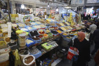 A woman walks past a shop at a market near Algiers, Tuesday, March 26, 2024. As Muslim-majority countries reckon with increased demand throughout Islam's holy month of Ramadan, is trying to flood new markets with pantry staples to stave off shortages that can cause prices to rise. (AP Photo/Anis Belghoul)