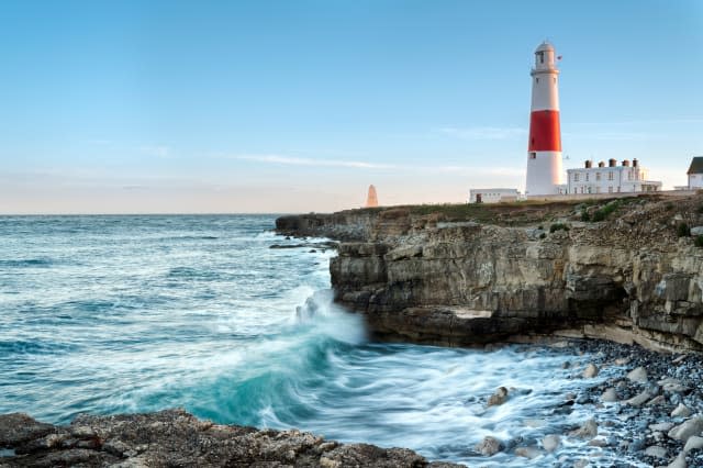 Waves crashing over rocks at Portland Bill lighthouse on the Jurassic Coast in Dorset