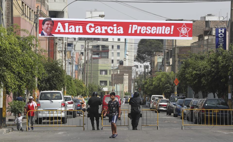 A sign featuring Peru's late President Alan Garcia reads in Spanish "Alan Garcia is here!" on the second day of his wake in Lima, Peru, Thursday, April 18, 2019. Garcia shot himself in the head and died Wednesday as officers waited to arrest him in a massive graft probe that has put the country's most prominent politicians behind bars and provoked a reckoning over corruption. (AP Photo/Martin Mejia)