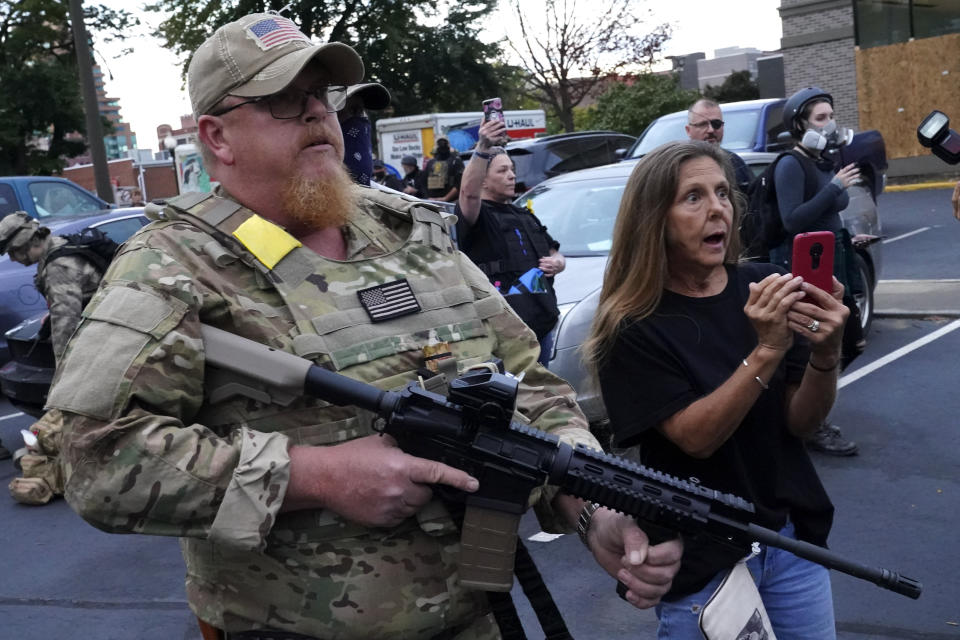 An armed counter-protester speaks with Black Lives Matter demonstrators, Thursday, Sept. 24, 2020, in Louisville, Ky. Authorities pleaded for calm while activists vowed to fight on Thursday in Kentucky's largest city, where a gunman wounded two police officers during anguished protests following the decision not to charge officers for killing Breonna Taylor. (AP Photo/John Minchillo)