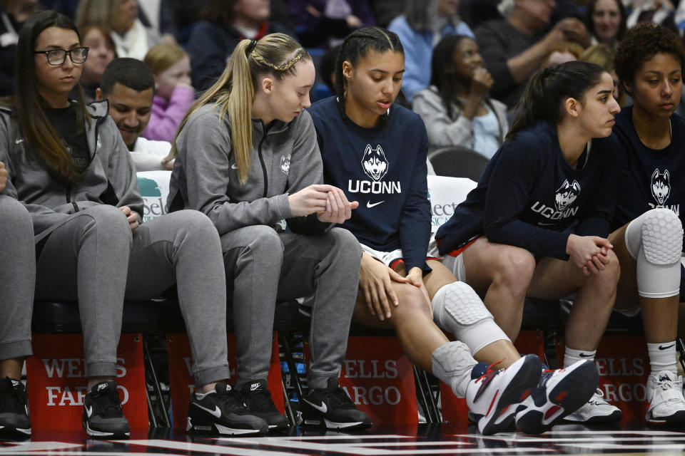 UConn's Paige Bueckers, second from left, looks down at teammate Azzi Fudd's knee in the second half of an NCAA college basketball game against Georgetown, Sunday, Jan. 15, 2023, in Hartford, Conn. Fudd left the game in the first half and did not return. (AP Photo/Jessica Hill)