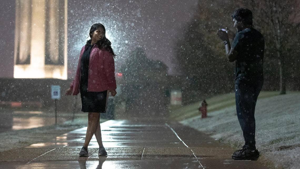 Krishna Perumalla takes a photo of Sree Gajjala as snow falls on Monday, Nov. 14, 2022 in Kansas City. Gajjala, who lived in India until moving to Kansas City in August to pursue her master’s degree, said it was her first time seeing snow.