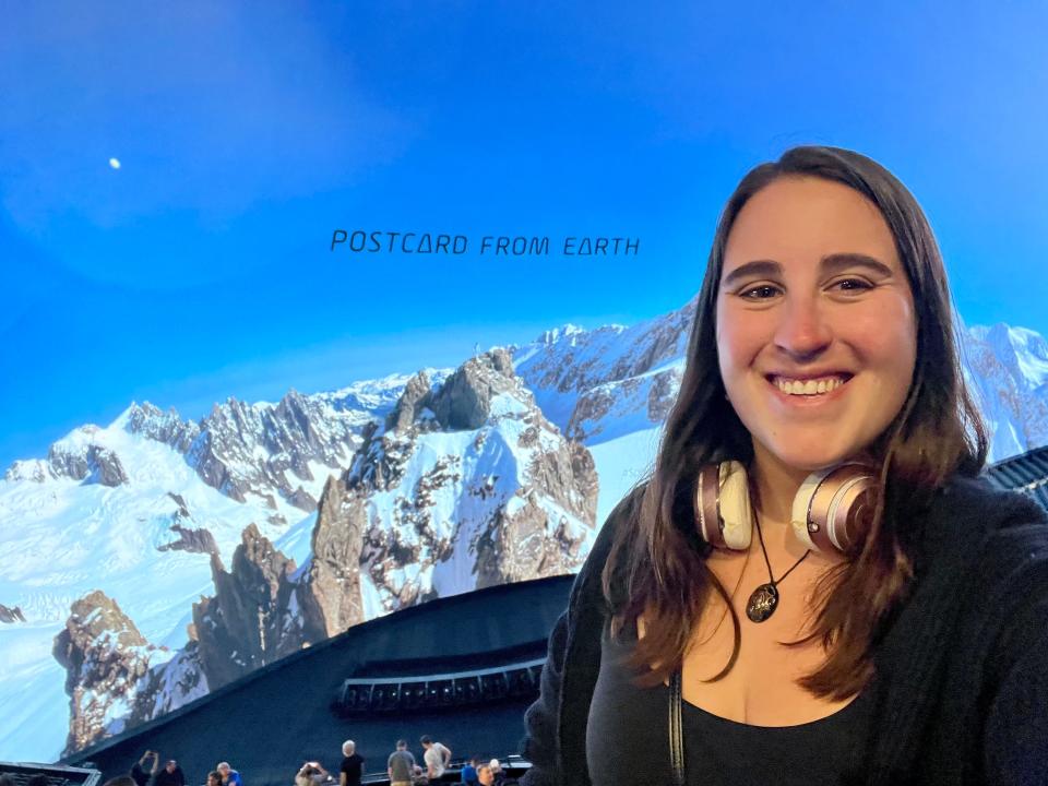 A selfie of the author in front of the auditorium screen with Postcard from Earth written.