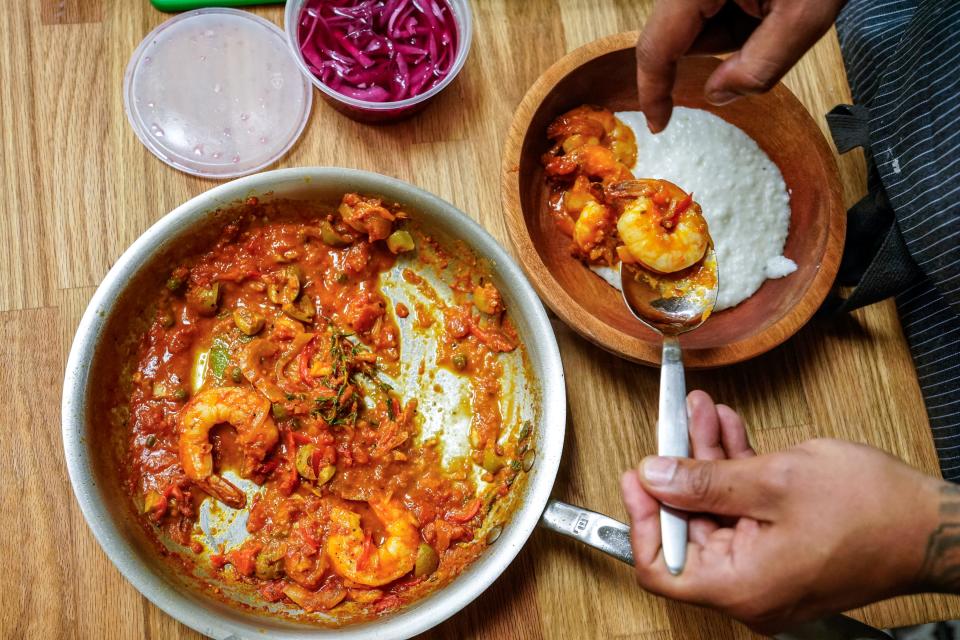 Digby Stridiron, chef and co-owner at Latha Restaurant & Bar, plates shrimp moqueca and coconut rice grits at the restaurant located within the Diaspora Collective in Phoenix on April 19, 2023.