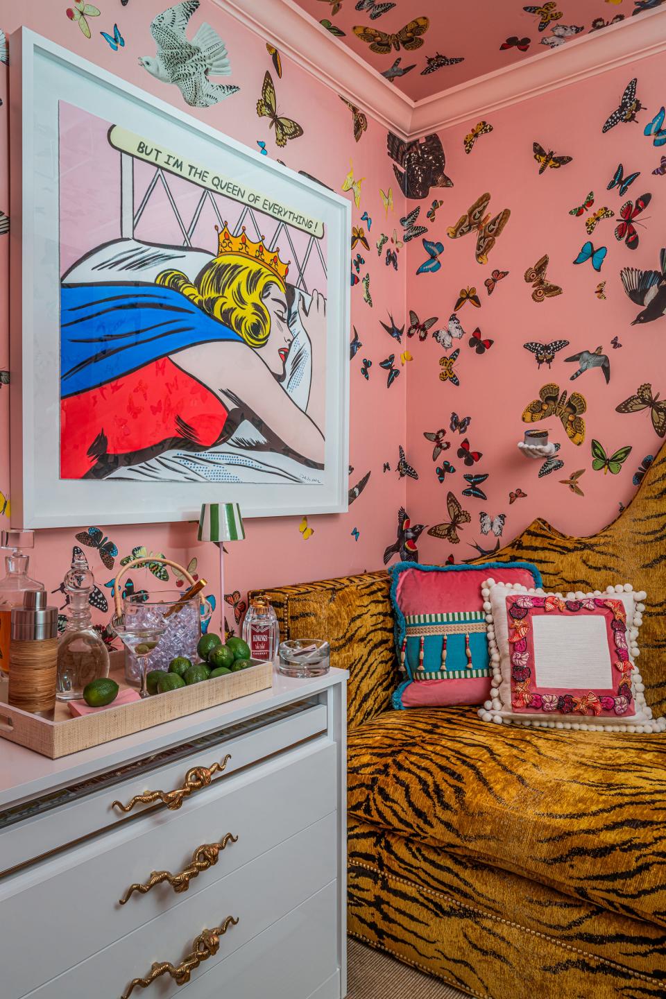 Hanging above a bureau filled with candy and vodka bottles is a piece of art by Nelson De La Nuez titled “But I’m the Queen of Everything!” in designer Megan Gorelick's "Gimme a Minute" retreat for the woman of the house at the Kips Bay Decorator Show House Palm Beach.