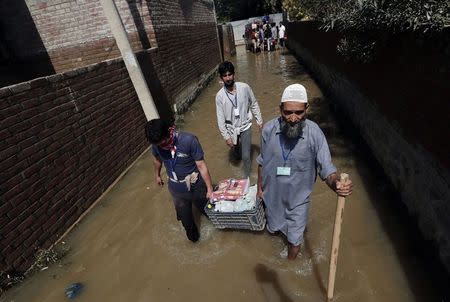 Members of Jamaat-e-Islami, a Muslim religious group, wade through flood waters as they carry relief material to be distributed among the stranded flood victims in Srinagar September 15, 2014. REUTERS/Adnan Abidi