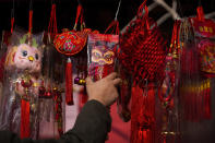 A man selects prosperity decorations on display for sale at a pavement shop on the eve of the Chinese Lunar New Year in Beijing, Friday, Feb. 9, 2024. (AP Photo/Andy Wong)
