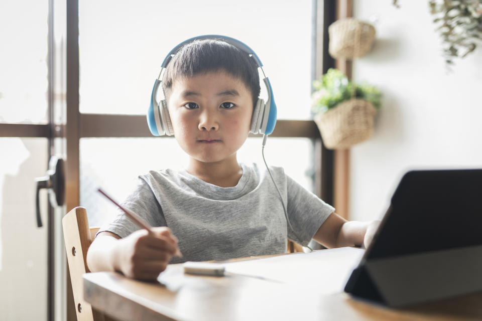 young kid wearing headphones with a pencil in hand