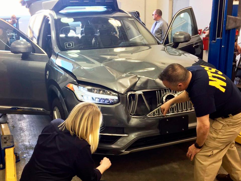 Investigators examine a driverless Uber SUV that fatally struck a woman in Tempe, Arizona.