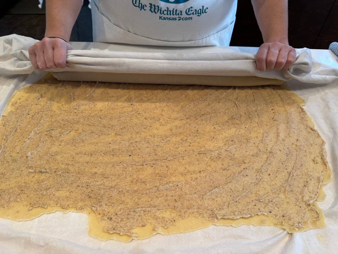 Katie Grover rolls out the dough for her povitica on a giant flour-sack towel passed down to her by her grandmother. She then uses the towel to help her roll up the filled dough. Denise Neil/The Wichita Eagle