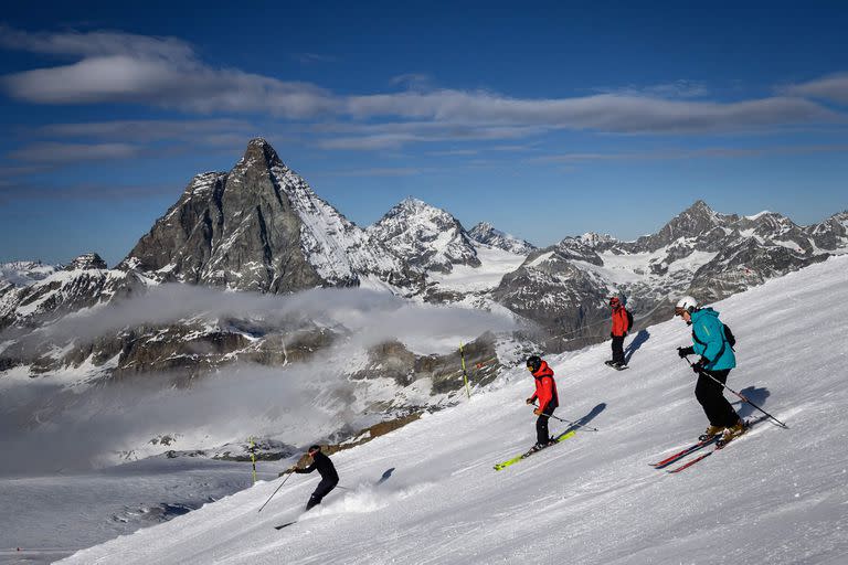 A photograph taken on November 28, 2020 shows skiers with the Matterhorn mountain as landscape near the 3,480-metre high Rifugio Guide del Cervino refuge at Testa Grigia peak between Zermatt Switzerland and Breuil-Cervinia, Italy. - Way up in the snowy Alps, the border between Switzerland and Italy has shifted due to a melting glacier, putting the location of an Italian mountain refuge in dispute. The border line runs along the drainage divide -- the point at which meltwater will run off down either side of the mountain towards one country or the other. But the Theodul Glacier's retreat means the watershed has crept towards the Rifugio Guide del Cervino, by the 3,480-metre high Testa Grigia peak -- and is gradually sweeping underneath the building. (Photo by Fabrice COFFRINI / AFP)