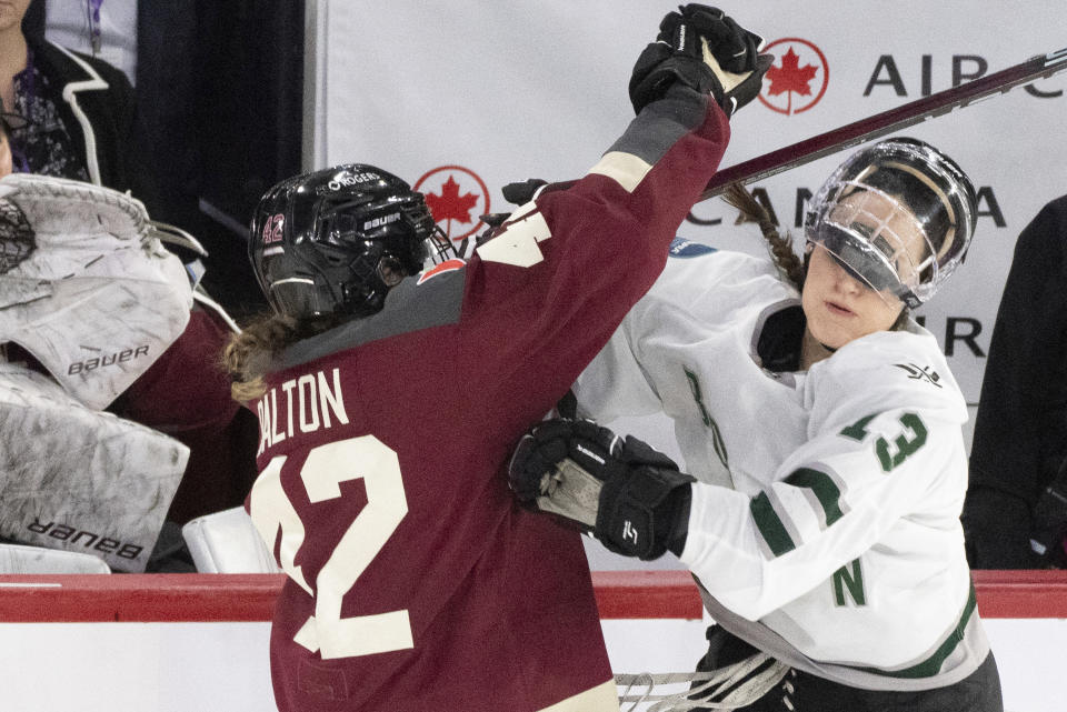 Montreal's Claire Dalton (42) and Boston's Kaleigh Fratkin (13) battle on the boards during second-period PWHL playoff hockey game action in Laval, Quebec, Saturday, May 11, 2024. (Christinne Muschi/The Canadian Press via AP)