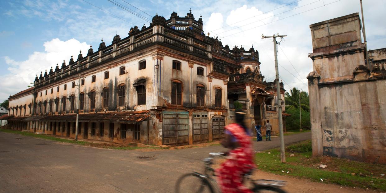 A cyclist is photographed in a blurry silhouette in front of a mansion in Chettinad in 2010.