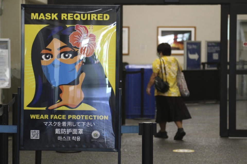 FILE - In this Oct. 2, 2020 file photo, a woman walks into the international airport in Honolulu. Hawaii officials are facing pressure to increase COVID-19 testing for travelers. The islands are weathering a record surge and federal guidelines are being changed to require negative virus tests from both vaccinated and unvaccinated travelers to the U.S. State leaders have resisted implementation of a two-test policy for arriving travelers despite evidence that more COVID-19 testing would help reduce the spread of disease, especially in an isolated destination location like Hawaii. (AP Photo/Caleb Jones, File)