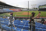 Fans wearing face masks to help protect against the spread of the new coronavirus take a selfie before the KBO league game between Doosan Bears and LG Twins in Seoul, South Korea, Sunday, July 27, 2020. Masked fans hopped, sang and shouted cheering slogans in baseball stadiums in South Korea on Sunday as authorities began bringing back spectators in professional sports games amid the coronavirus pandemic. (AP Photo/Ahn Young-joon)