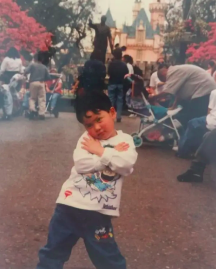 a small boy posing dramatically with his head tilted and arms folded over his body