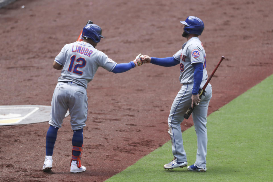 New York Mets' Francisco Lindor, left, bumps fists with Jose Peraza, right, after he scored on a single hit by Billy McKinney in the third inning of a baseball game against the San Diego Padres Sunday, June 6, 2021, in San Diego. (AP Photo/Derrick Tuskan)