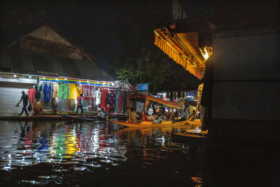 A Kashmiri boatman rows his boat carrying Indian tourists at a market in the interior of Dal Lake in Srinagar, Indian controlled Kashmir, Monday, Aug. 2, 2021. Dal Lake appears pristine in the area where hundreds of exquisitely decorated houseboats bob on its surface for rent by tourists and honeymooners. But farther from shore, the lake is a mixture of mossy swamps, thick weeds, trash-strewn patches and floating gardens made from rafts of reeds. (AP Photo/Mukhtar Khan)