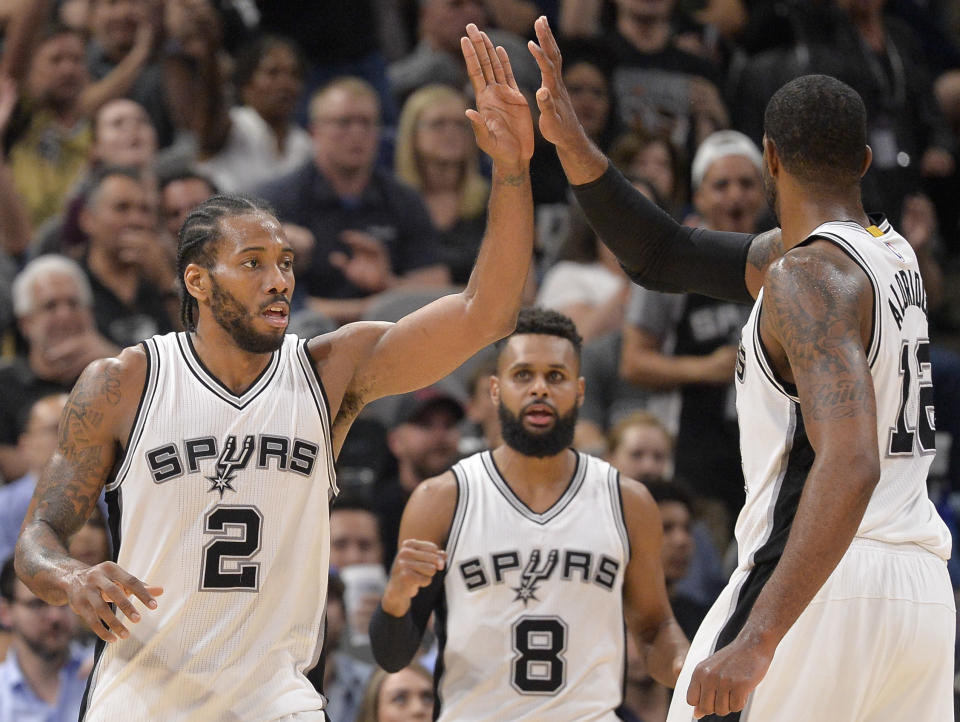 San Antonio Spurs forward Kawhi Leonard (2) celebrates a basket with Spurs' LaMarcus Aldridge, right, and Patty Mills, of Australia, during the first half of an NBA basketball game against the Cleveland Cavaliers, Monday, March 27, 2017, in San Antonio. (AP Photo/Darren Abate)